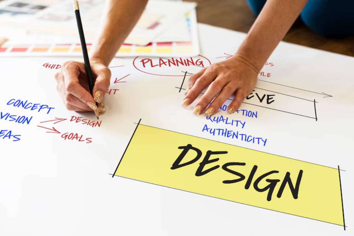 A person writes on a large sheet of paper, outlining a design plan with keywords like goals, concept, and quality highlighted.