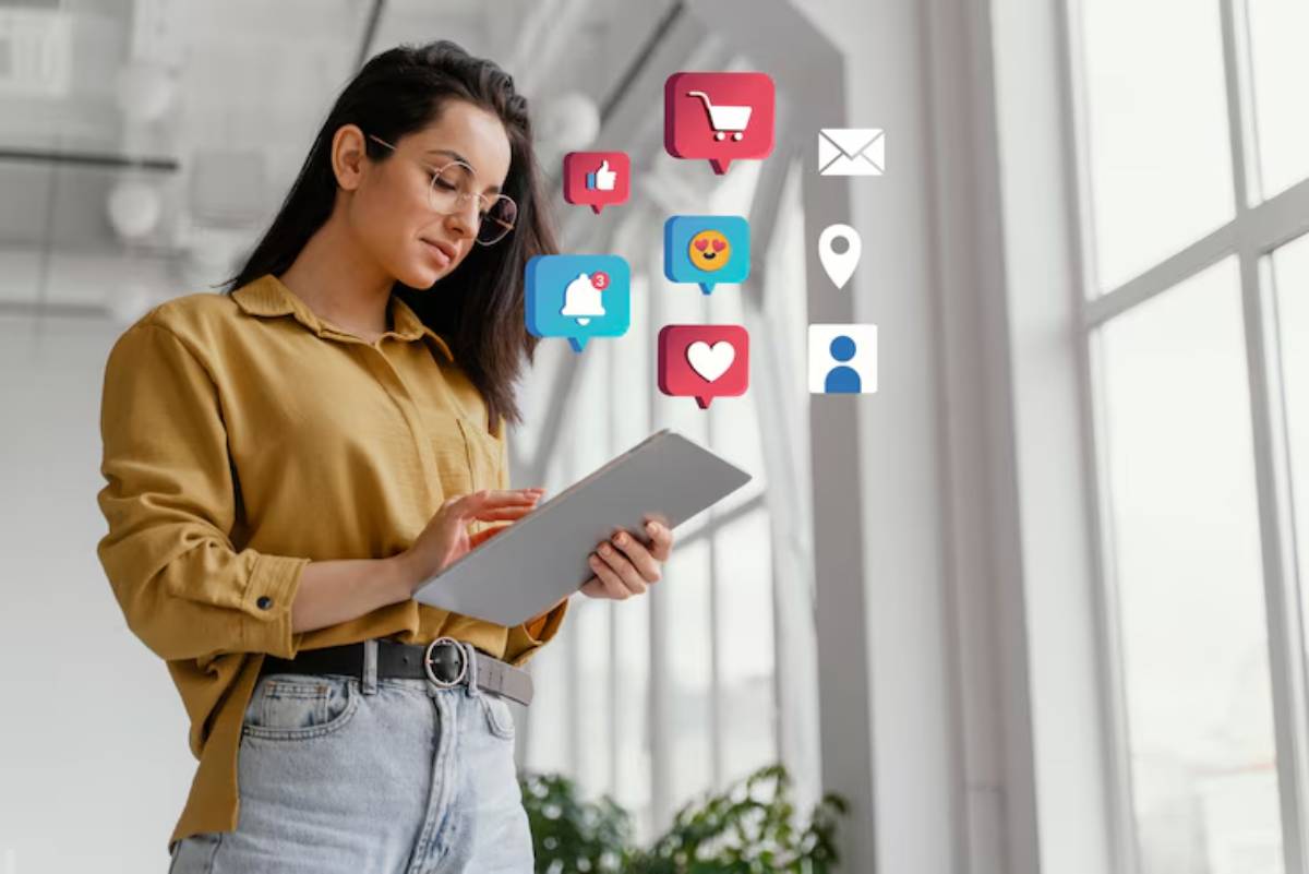 A person in a yellow shirt uses a tablet surrounded by colorful digital icons representing social media and notifications.