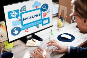 A person typing on a keyboard in front of a computer screen displaying the word BACKLINKS surrounded by various digital icons.