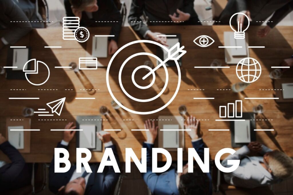 Aerial view of a business meeting with people discussing, surrounded by branding icons like a target, globe, and light bulb.