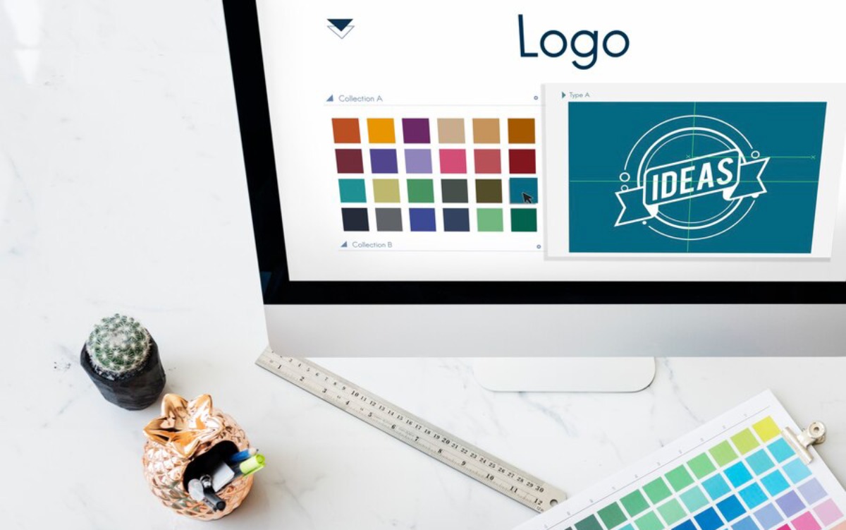 A computer screen displaying logo design options with color palettes and a blue IDEAS graphic, alongside a ruler and stationery.